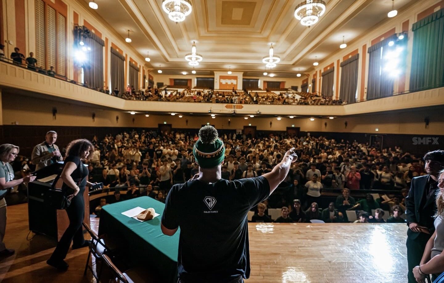 Caleb addressing a packed auditorium