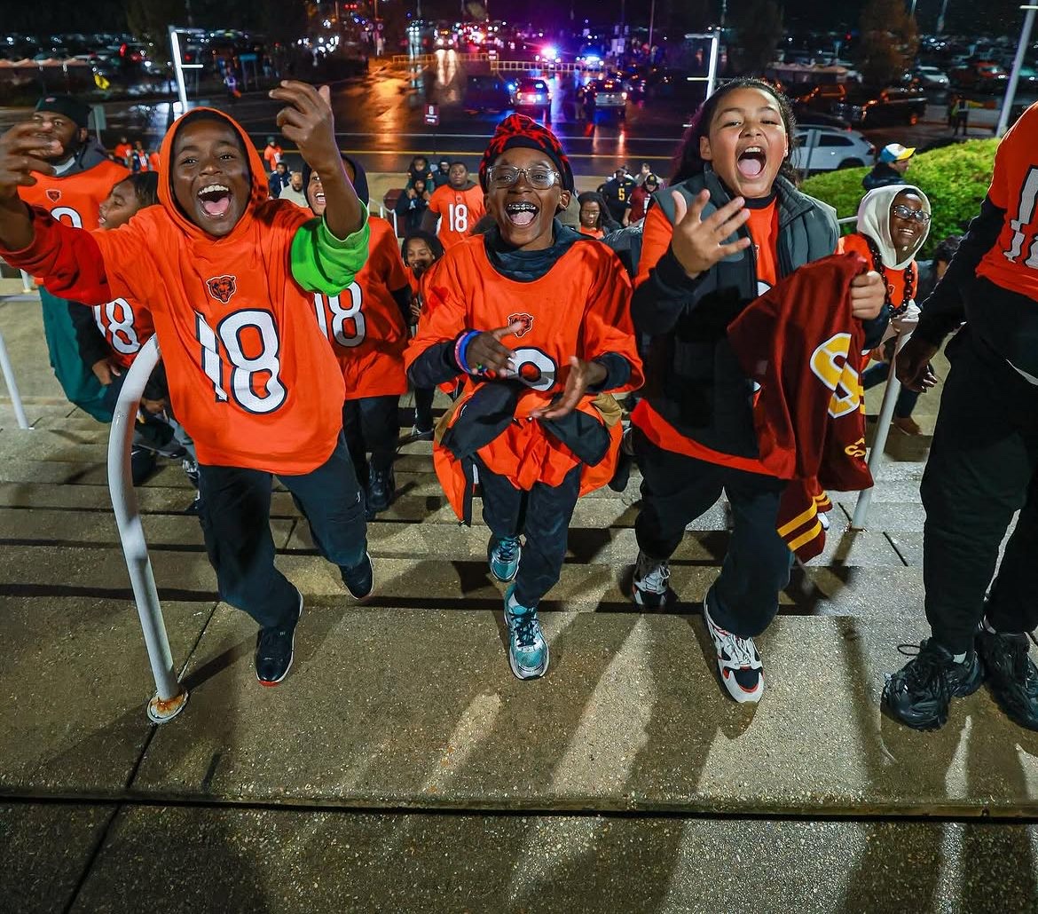 Fans in orange jerseys entering the stadium at night